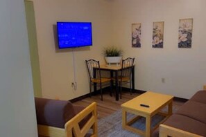 Un salon avec un téléviseur, une table à manger avec des chaises et un canapé.