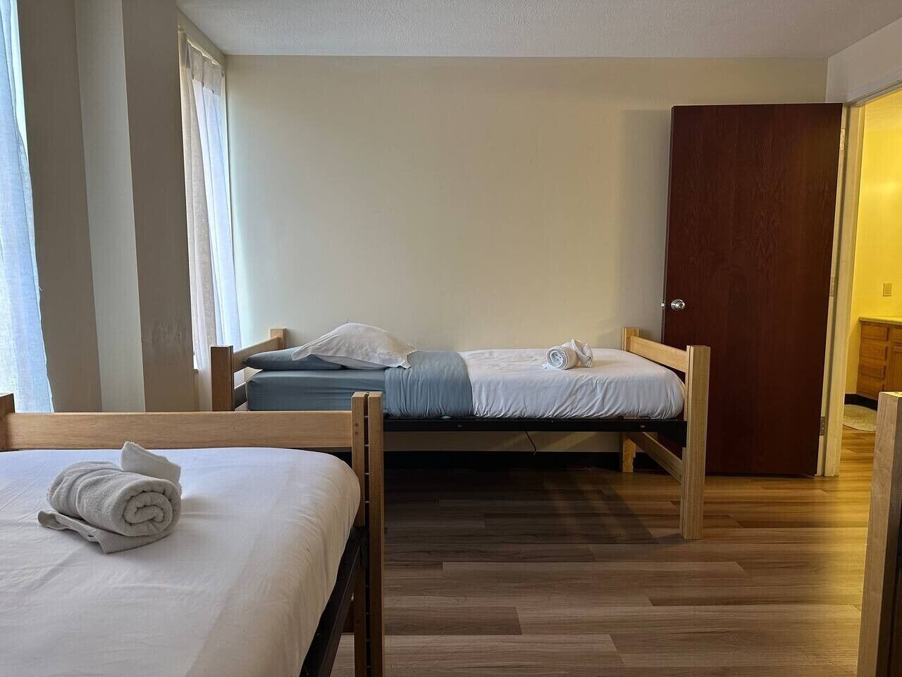 Quarto com duas camas de madeira, um guarda-roupa de madeira e chão de madeira.