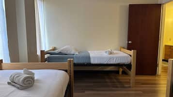Une pièce avec deux lits en bois, une armoire en bois et un plancher en bois.