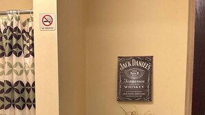 A bathroom with a toilet, a no-smoking sign, a Jack Daniel's whiskey sign, and a shower curtain. - 2BR 2BA Downtown Apt | Spacious + Walkable (Pittsburgh)