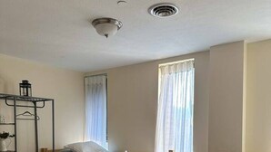 A room with two wooden beds, a metal wardrobe, and a window with curtains. - 2BR 2BA Downtown Apt | Spacious + Walkable (Pittsburgh)