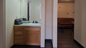 A bathroom with wooden cabinets, a sink, and a mirror. - 2 Bedroom Downtown Apartment | Perfect for Groups (Pittsburgh)