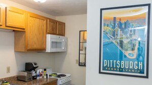 A kitchen with wooden cabinets, a microwave, a toaster, a stove, and a sink. - 2 Bedroom Downtown Apartment | Perfect for Groups (Pittsburgh)