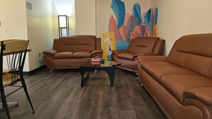 A living room with two brown leather sofas, a glass coffee table, and a colorful cityscape mural on the wall. - 2 Bedroom Downtown Apartment | Perfect for Groups (Pittsburgh)