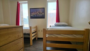 A room with two wooden beds, a wooden dresser, and a cityscape painting on the wall. - 2 Bedroom Downtown Apartment | Perfect for Groups (Pittsburgh)