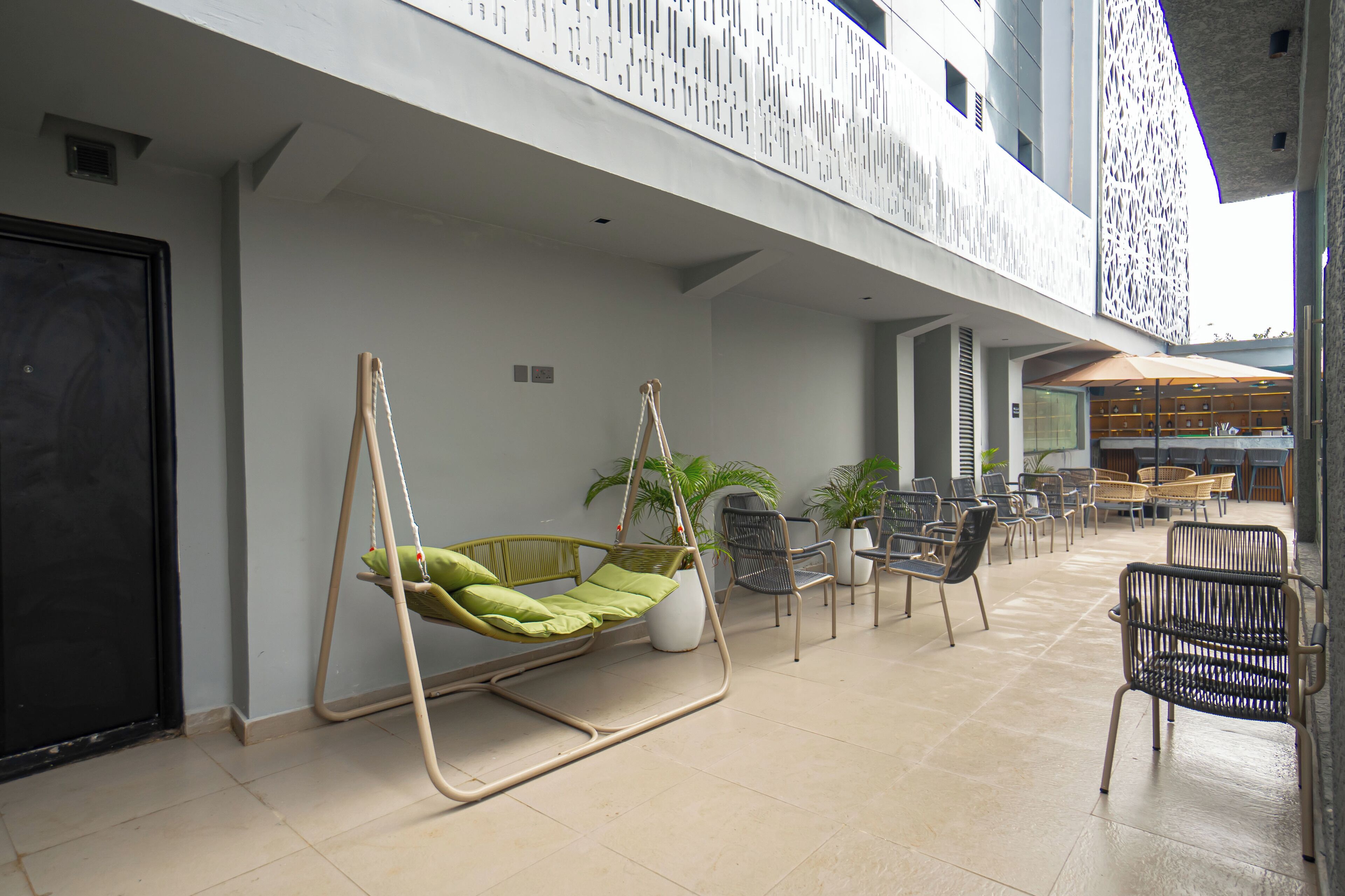 A modern indoor seating area with a hanging chair, multiple chairs, and potted plants.