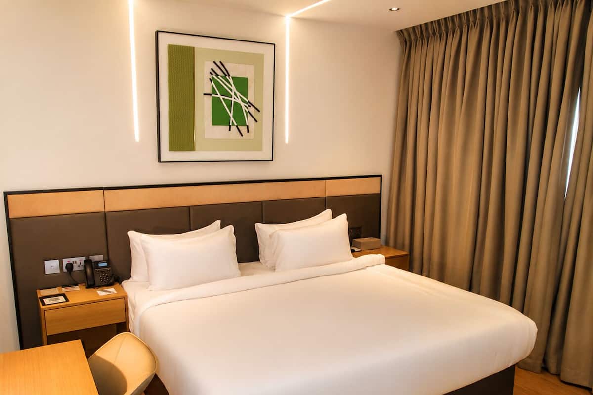 Une chambre d’hôtel avec un grand lit, deux tables de chevet, un bureau et une chaise.