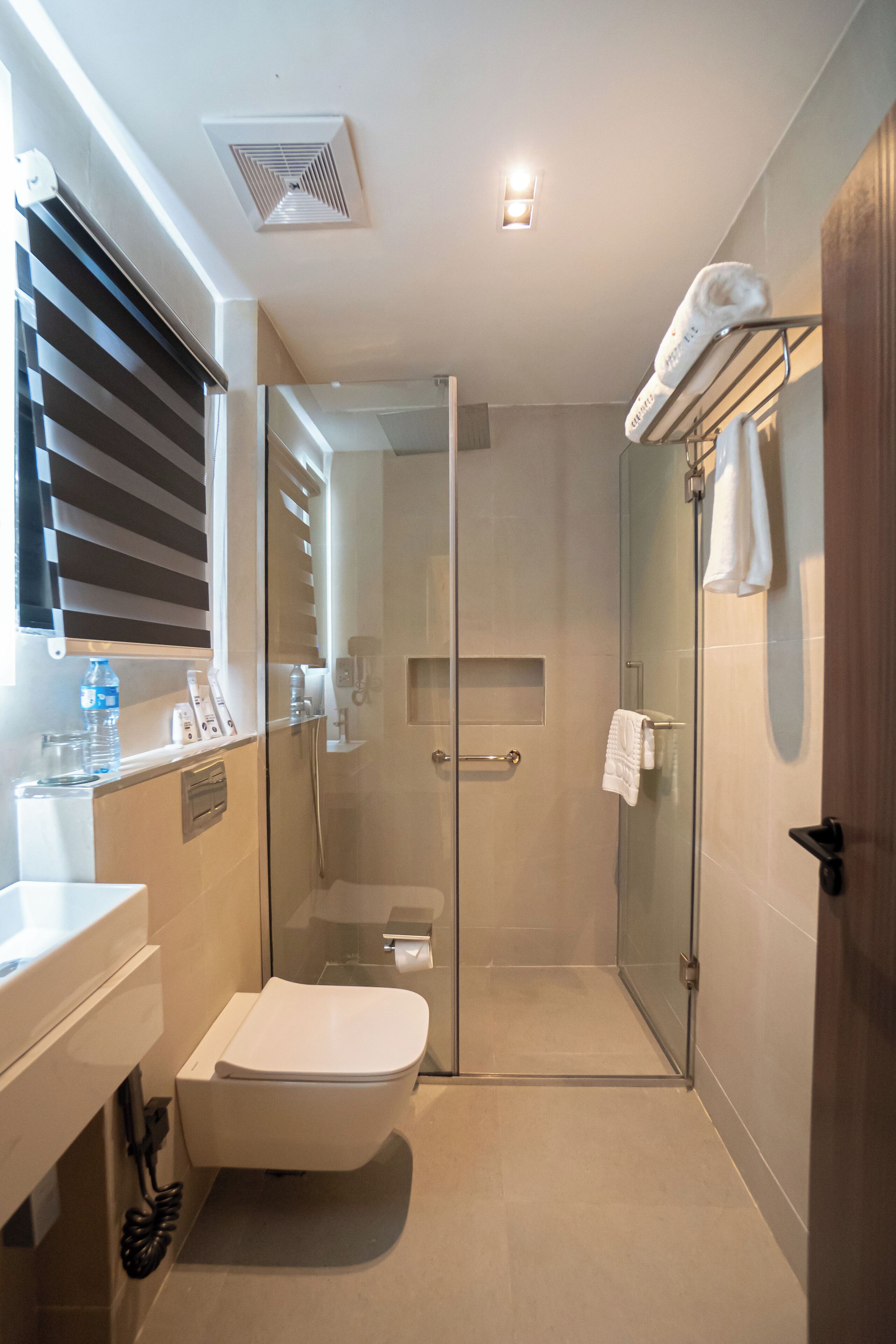 Een moderne badkamer met een douchecabine van glas, een wit toilet en een handdoekrek met een handdoek.