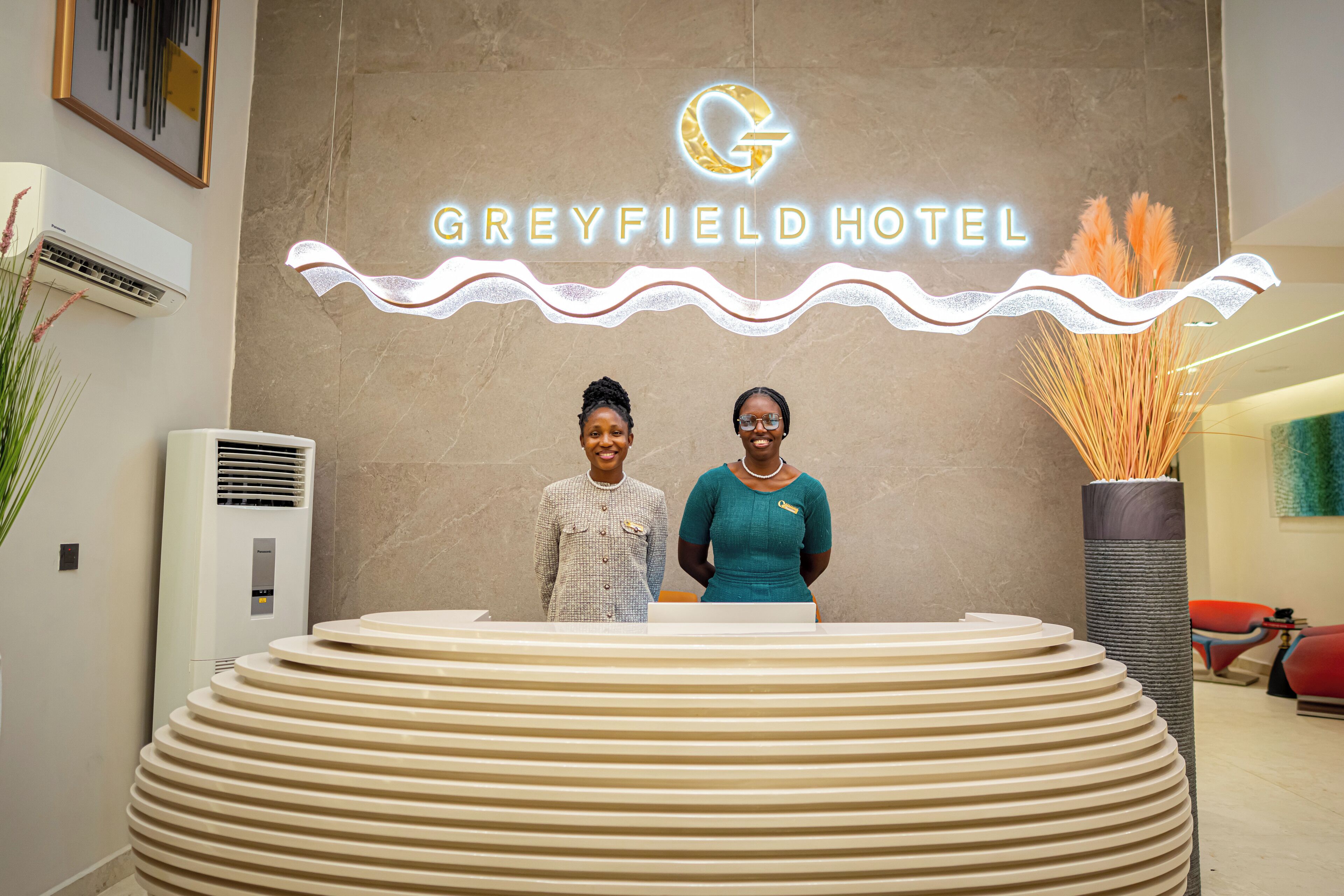 A reception desk at Greyfield Hotel with a modern design and a logo above the name.