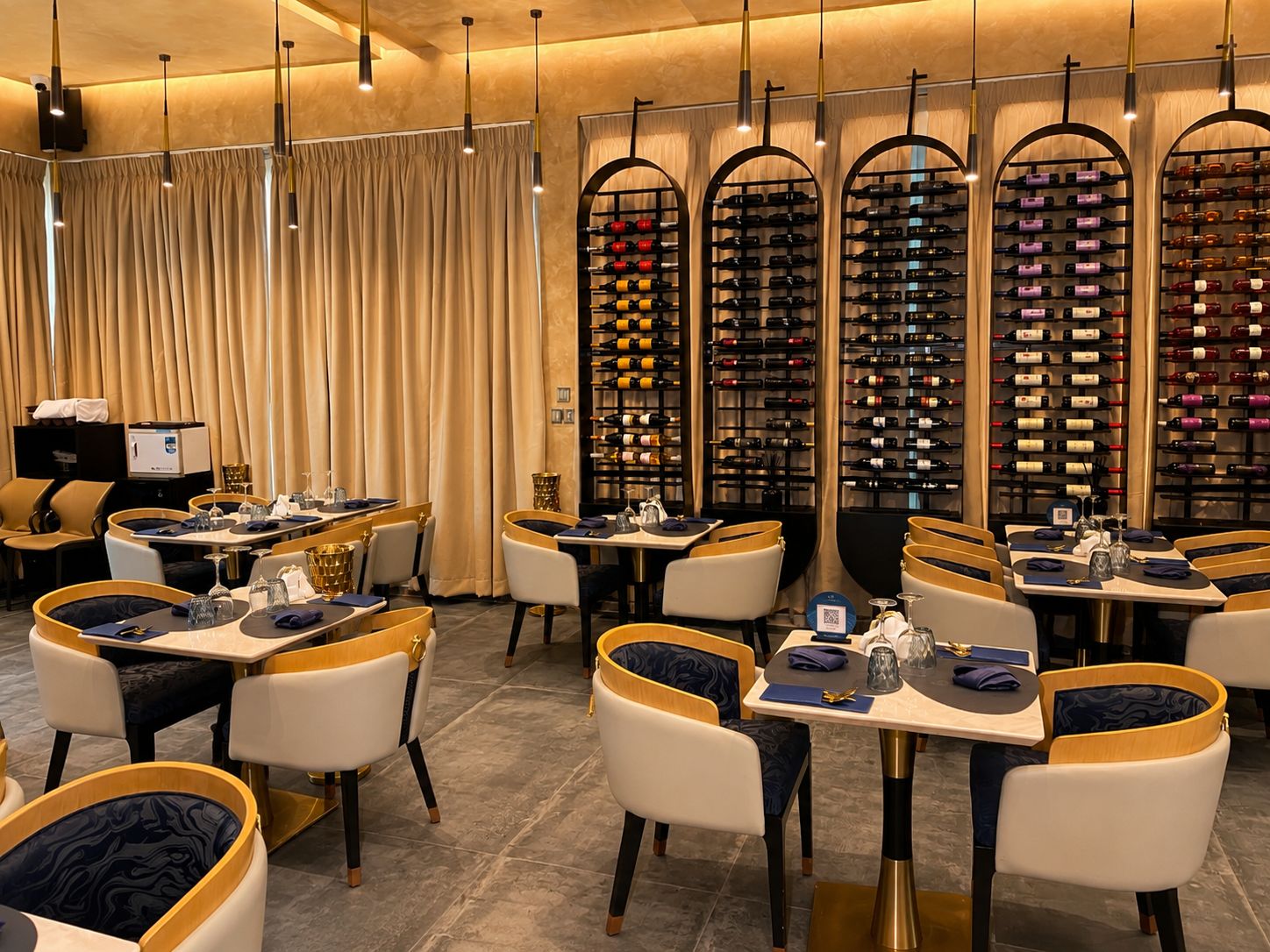 Un restaurant avec des tables et des chaises, un présentoir à bouteilles de vin et un rideau.
