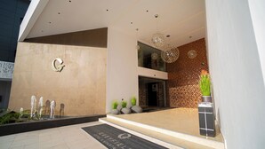 Una entrada de edificio moderna con una fuente de agua, un mostrador de recepción y una pared decorativa.