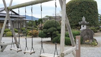 A wooden swing set in a garden with a pagoda and rock formations.