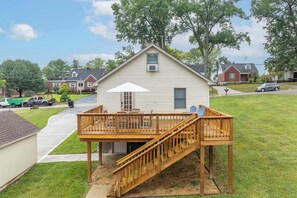 A single-story house with a wooden deck and a staircase leading to a covered patio area.