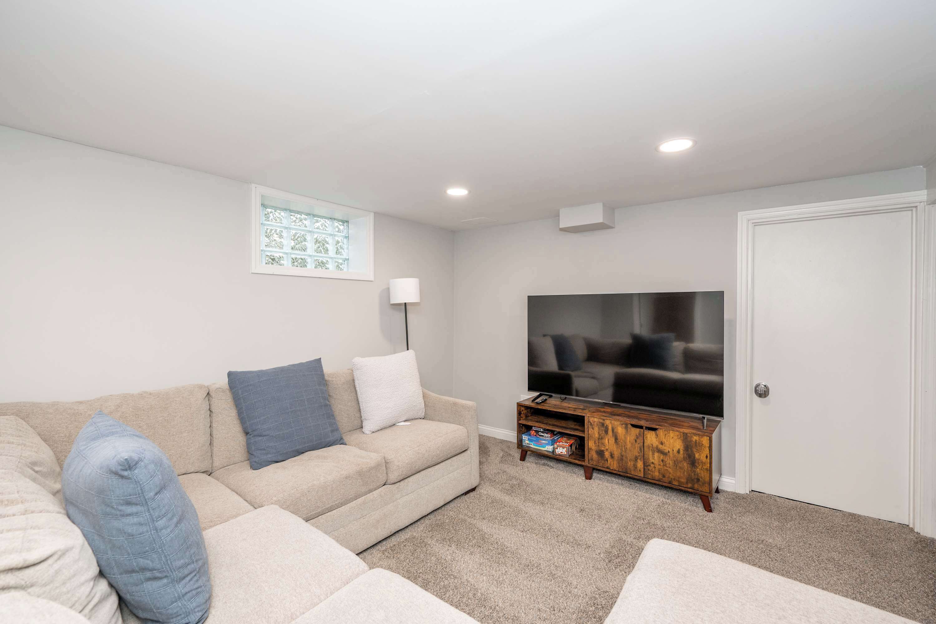 A living room with a beige sofa, a flat-screen TV, and a wooden cabinet.