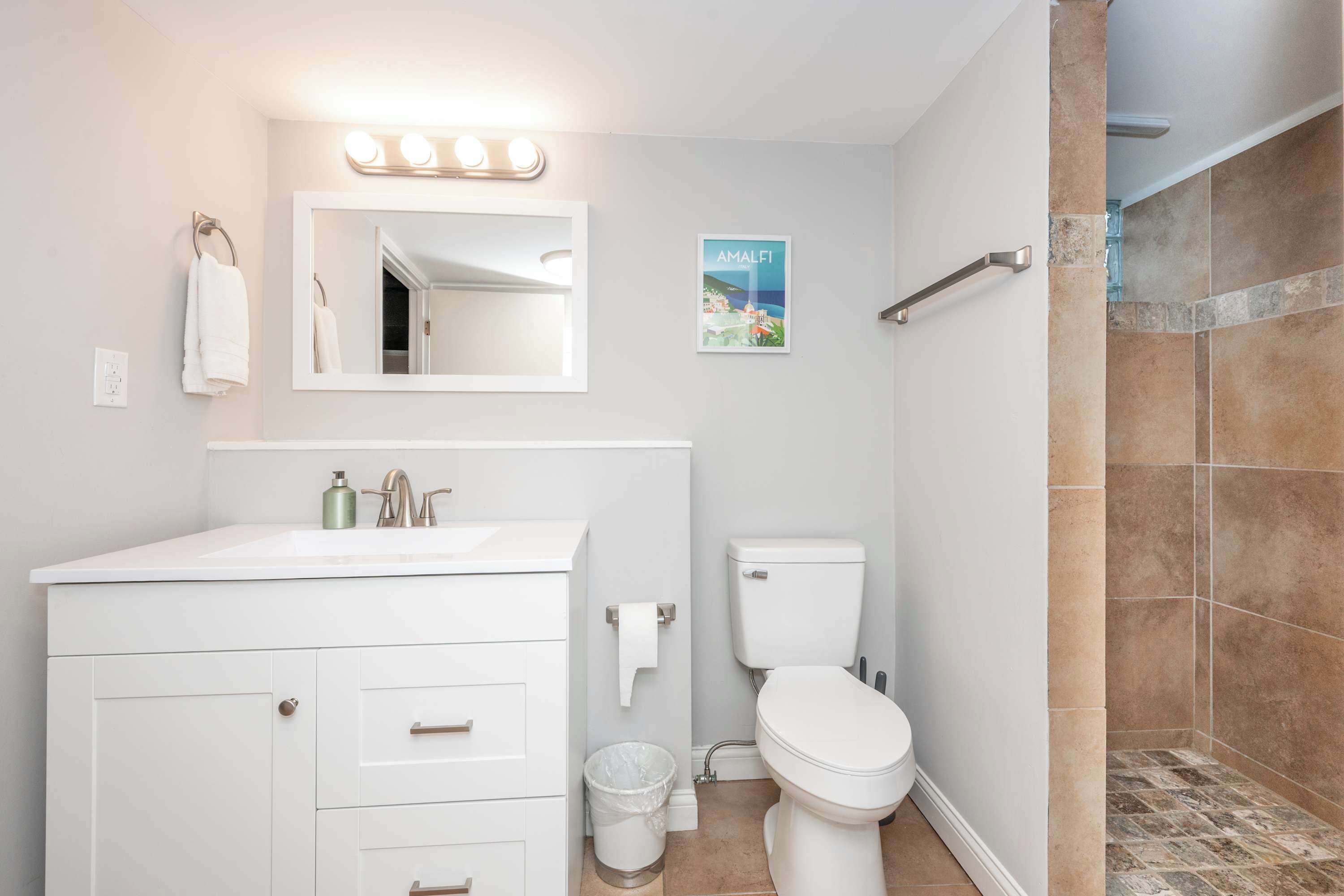 Un baño moderno con tocador blanco, inodoro y zona de ducha.