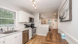 Una cocina moderna con armarios blancos, electrodomésticos de acero inoxidable y encimera de madera.