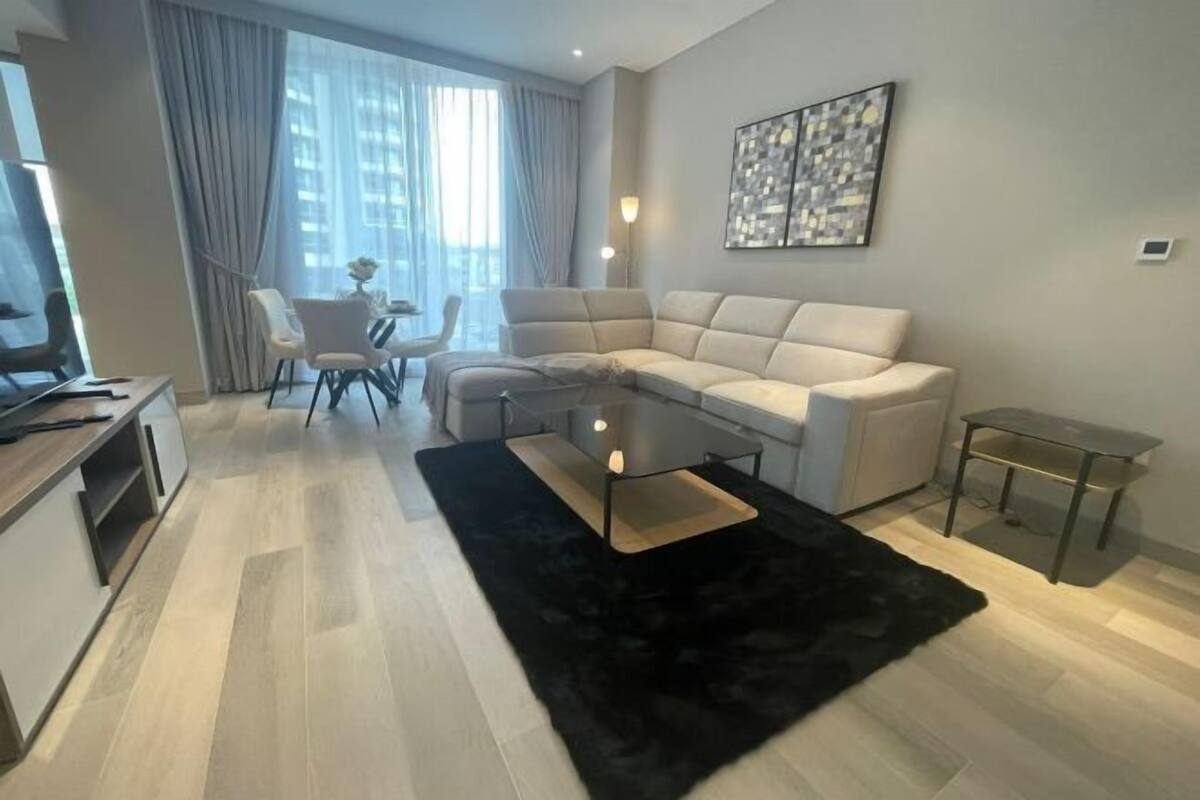 A modern living room with a sofa, a coffee table, a TV, and a dining area with chairs.