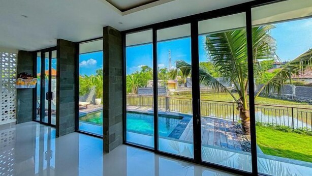 A modern room with large windows, a pool, and a view of a tropical landscape. - Dajan Dukuh Villa (2 Bedroom Villa with Minimum Stay 2 Night) (Bali)
