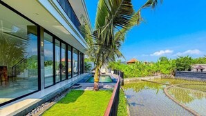 A modern building with large glass windows, a well-maintained lawn, and a water feature. - Dajan Dukuh Villa (2 Bedroom Villa with Minimum Stay 2 Night) (Bali)