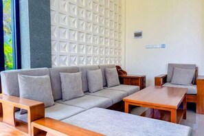 A modern living room with a grey sofa, two wooden side tables, and a white textured wall. - Dajan Dukuh Villa (2 Bedroom Villa with Minimum Stay 2 Night) (Bali)