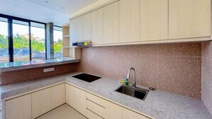 A modern kitchen with a granite countertop, a sink, and light-colored cabinets. - Dajan Dukuh Villa (2 Bedroom Villa with Minimum Stay 2 Night) (Bali)