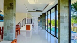 A modern interior with a polished floor, a staircase, and large windows overlooking a pool. - Dajan Dukuh Villa (2 Bedroom Villa with Minimum Stay 2 Night) (Bali)