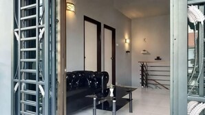 A modern interior with a sofa, a dining table, and a staircase. - Stylish Blue Water Home w/ Pool (Tebrau)