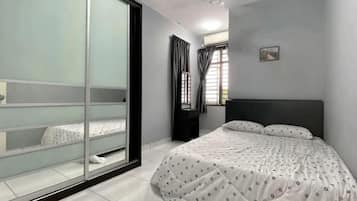 Een slaapkamer met een bed, een schuifdeur, een raam met gordijnen en een klein schilderij aan de muur.