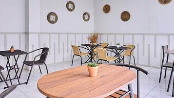 Un comedor moderno con mesas redondas, sillas de metal negro y lámparas colgantes tejidas.