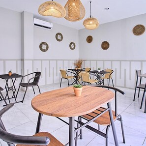 A modern dining area with round tables, black metal chairs, and woven pendant lights. - Bale Puri (West Jakarta)