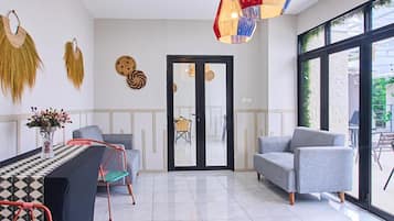 Un interior moderno con comedor, dos sofás, una lámpara colgante colorida y un ventanal grande.