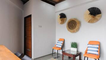 A conference room with a wooden table, two chairs, a small table with a plant, and decorative wall fans.