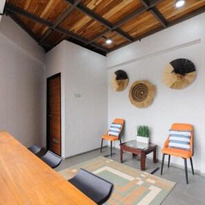 A conference room with a wooden table, two chairs, a small table with a plant, and decorative wall fans. - Bale Puri (West Jakarta)
