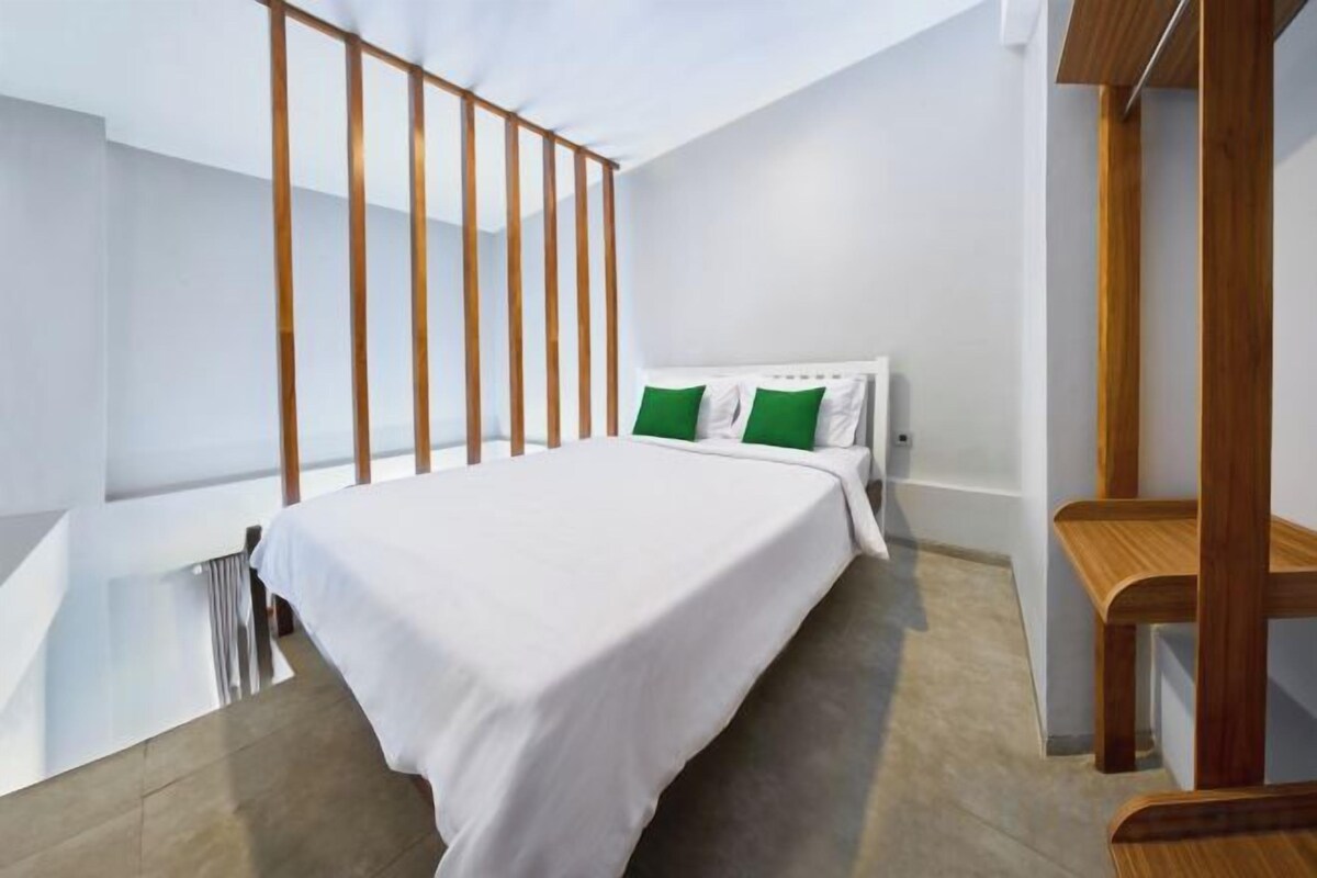 A modern bedroom with a large bed, a wooden headboard, and a view of the outdoors.