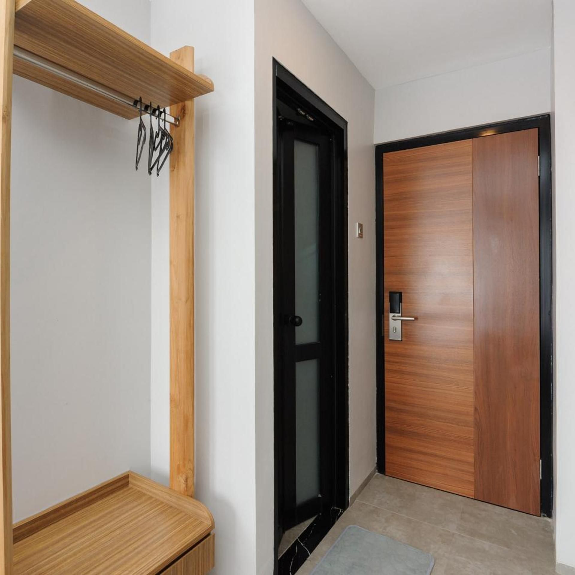 Un pasillo con un banco de madera, un perchero y una puerta con un picaporte moderno.