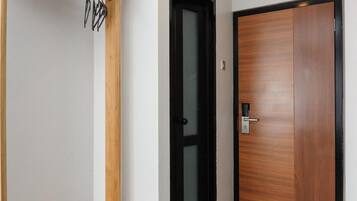 Un pasillo con un banco de madera, un perchero y una puerta con un picaporte moderno.