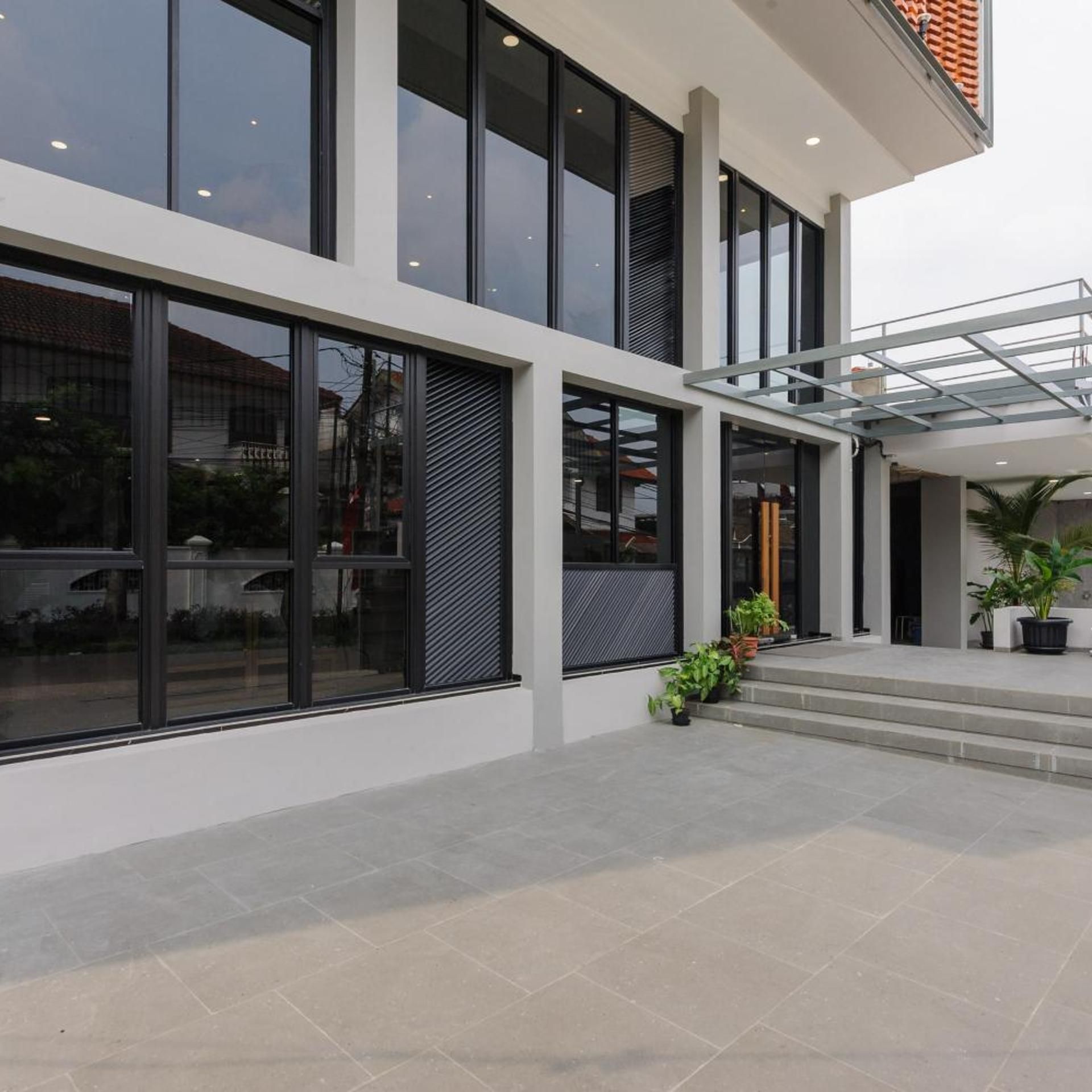 A modern building with large windows, a covered entrance, and a tiled floor.