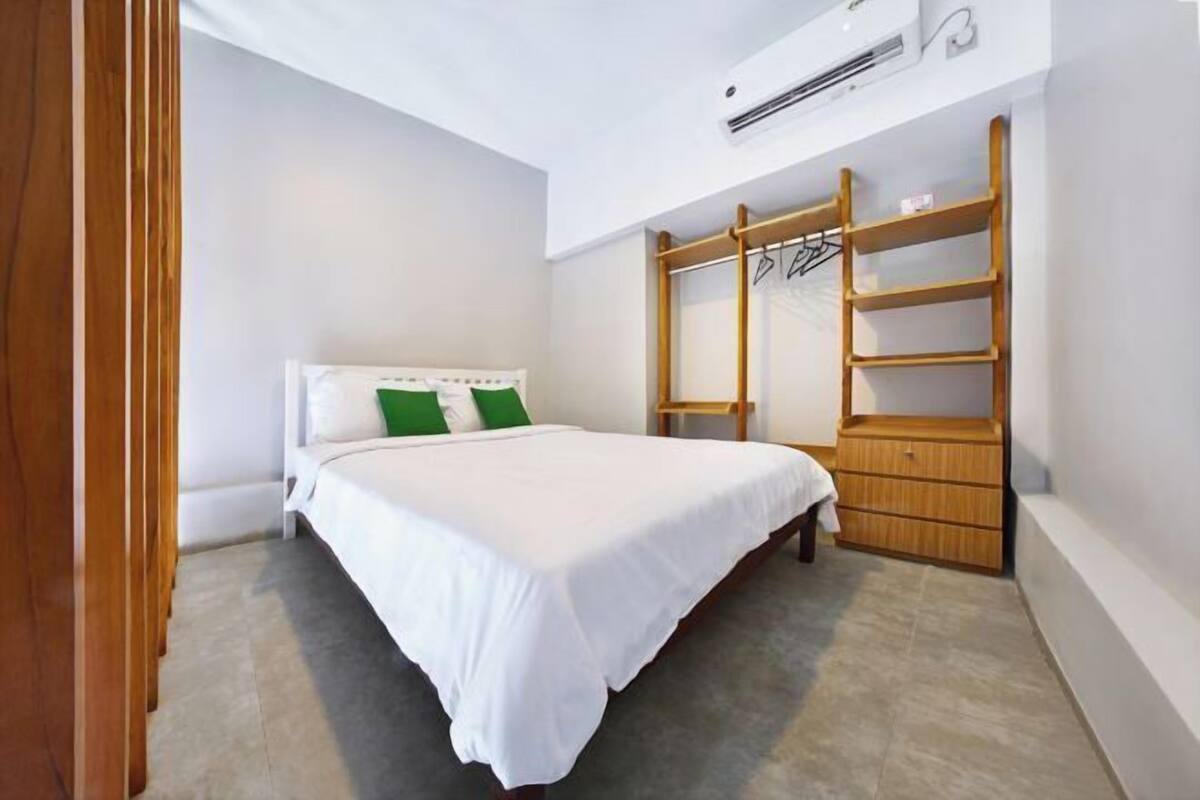Un dormitorio con cama, armario y aire acondicionado instalado.