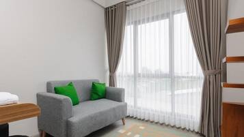 A modern room with a grey sofa, green cushions, a wooden side table, and a patterned rug.