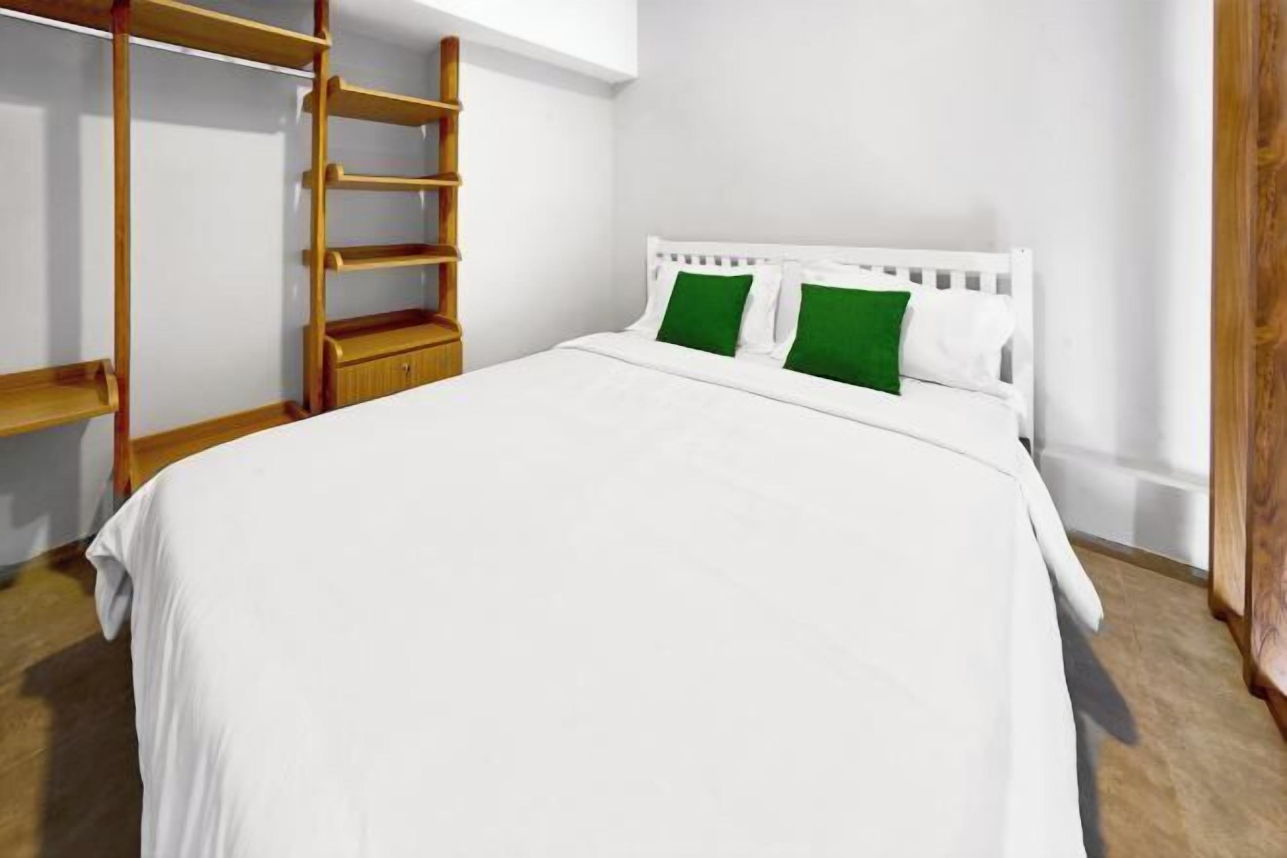 Ein Schlafzimmer mit einem weißen Bett, grünen Kissen, einer Holzleiter und einem weißen Kopfteil.