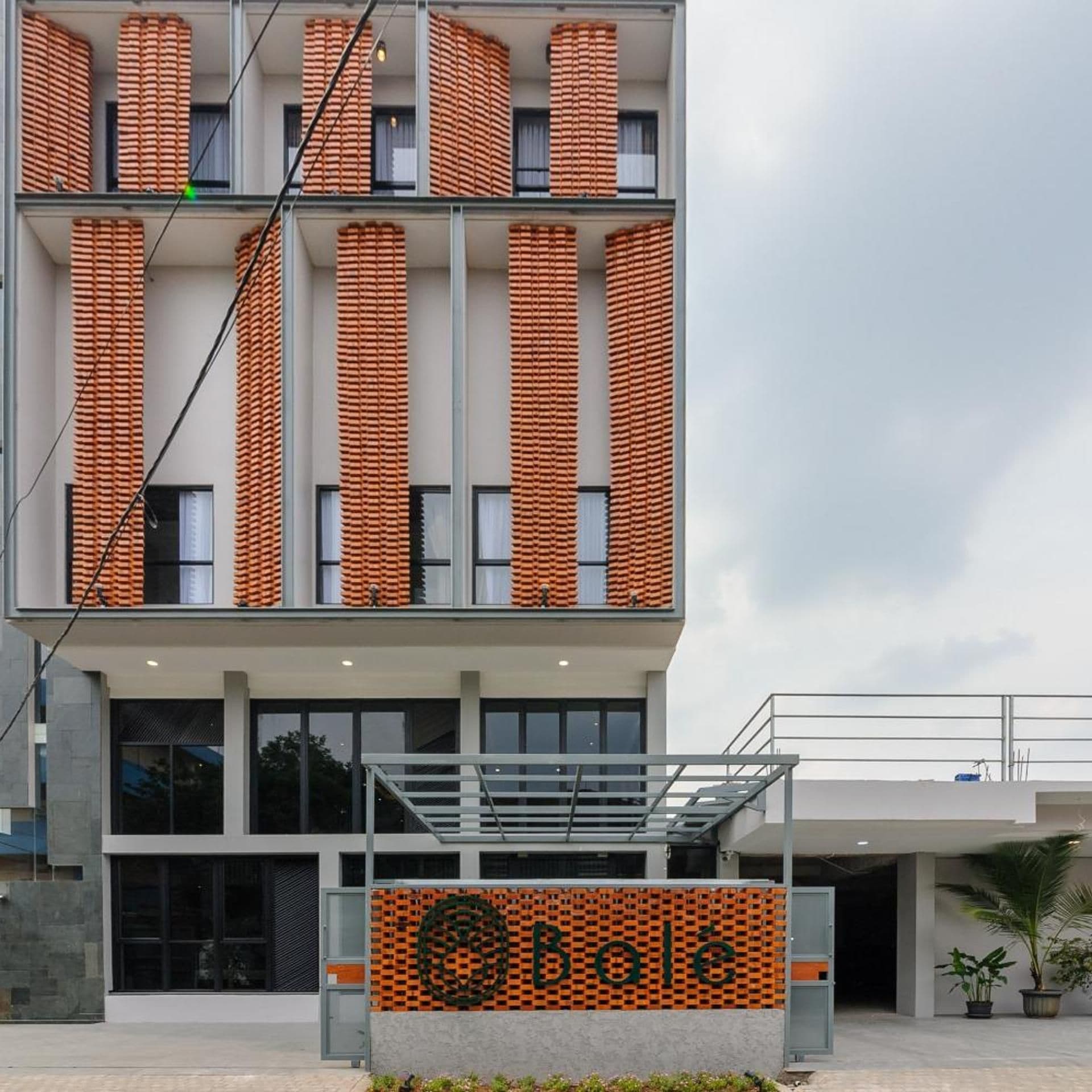 A modern building with a unique brick facade, large windows, and a prominent entrance with a logo.