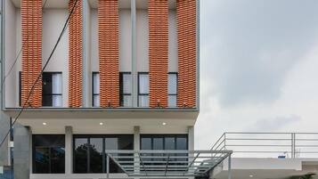 A modern building with a unique brick facade, large windows, and a prominent entrance with a logo.