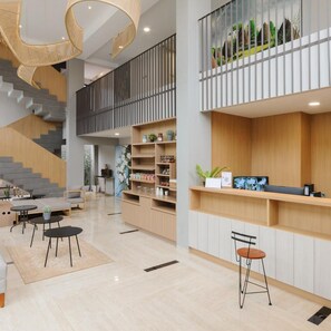 A modern interior with a staircase, seating area, and a reception desk. - Bale Puri (West Jakarta)