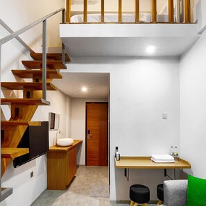 A modern interior with a wooden staircase, a small kitchenette, and a compact bathroom. - Bale Puri (West Jakarta)