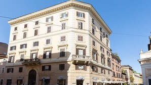 A multi-story building with a classical architectural style, featuring a central entrance with an archway, multiple windows with shutters, and a balcony on the second floor. - Rental in Rome Ripa Apartment (Rome)