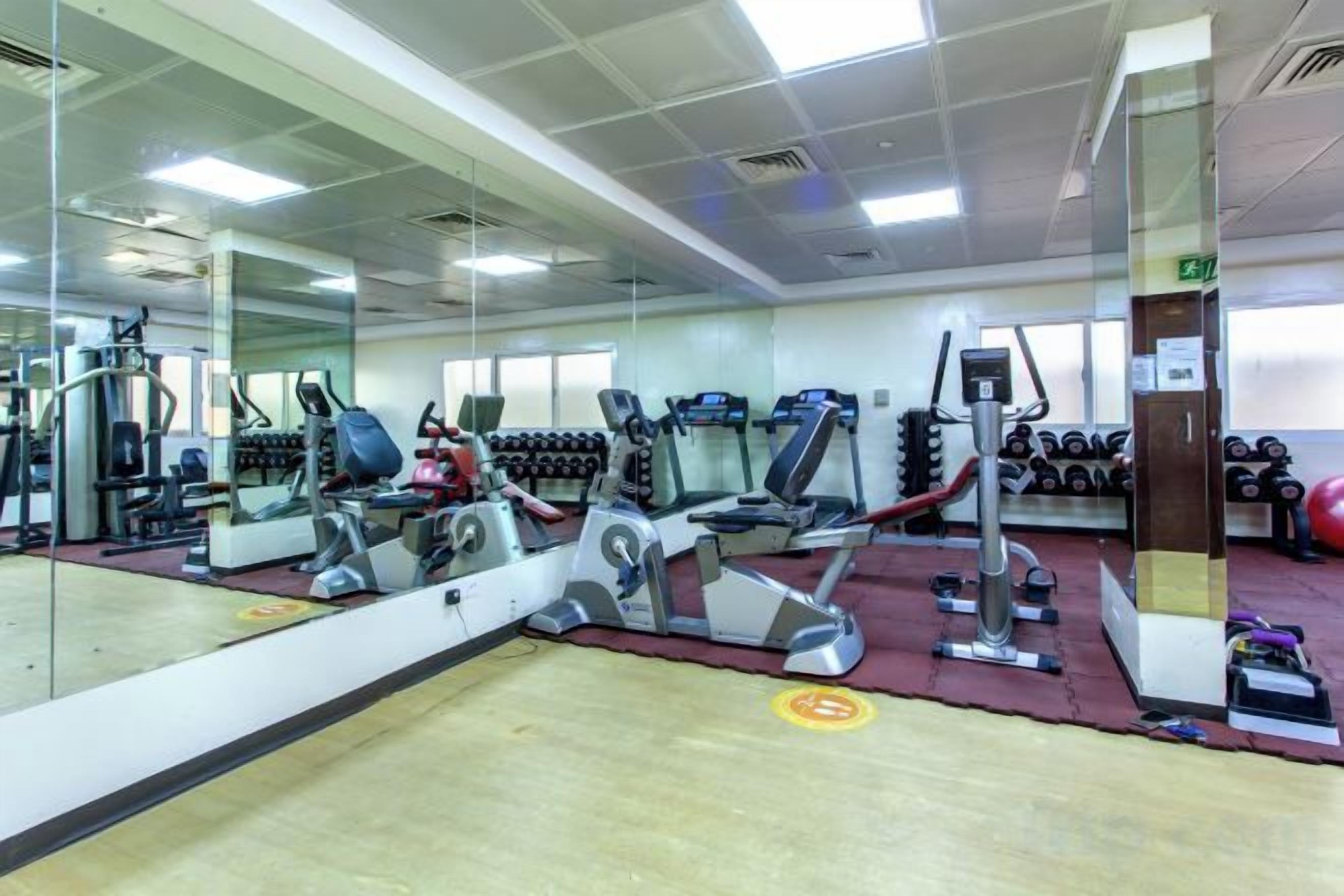 A gym with exercise equipment, a large mirror, and a red carpet.