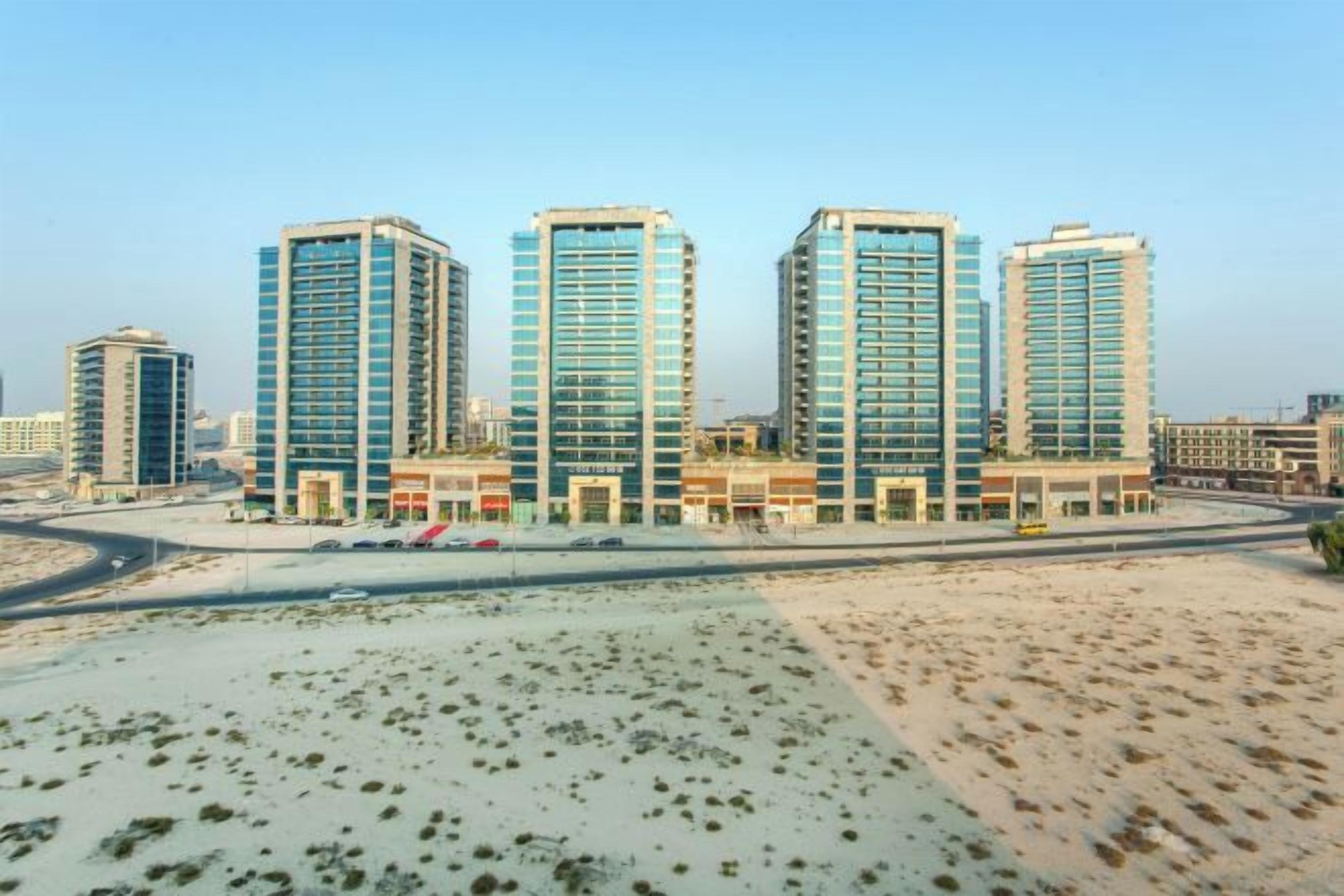 A modern hotel with multiple high-rise buildings, a central courtyard, and a desert landscape.