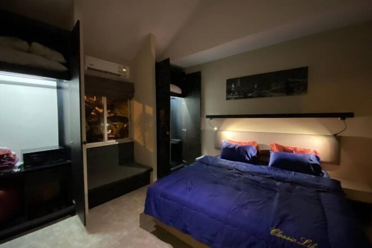 Quarto com cama, cabeceira, mesa de cabeceira e janela.