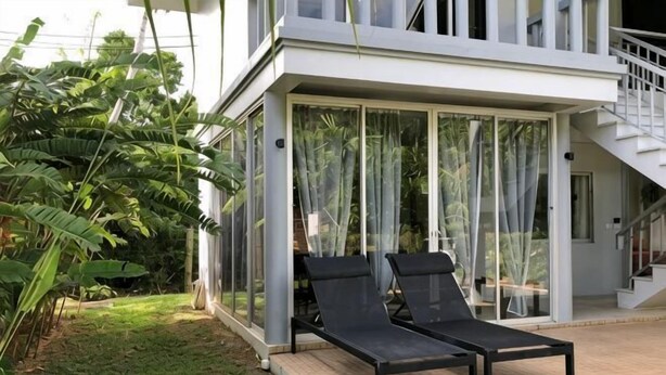 A modern house with a glass-enclosed patio, two black lounge chairs, and a staircase leading to an upper level. - 217 Casa Del Mar Pool Villa@Casa Sakoo Phuket (Phuket)