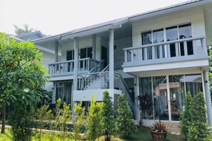 Un bâtiment à deux étages doté d’un balcon, d’un escalier et d’un espace jardin.